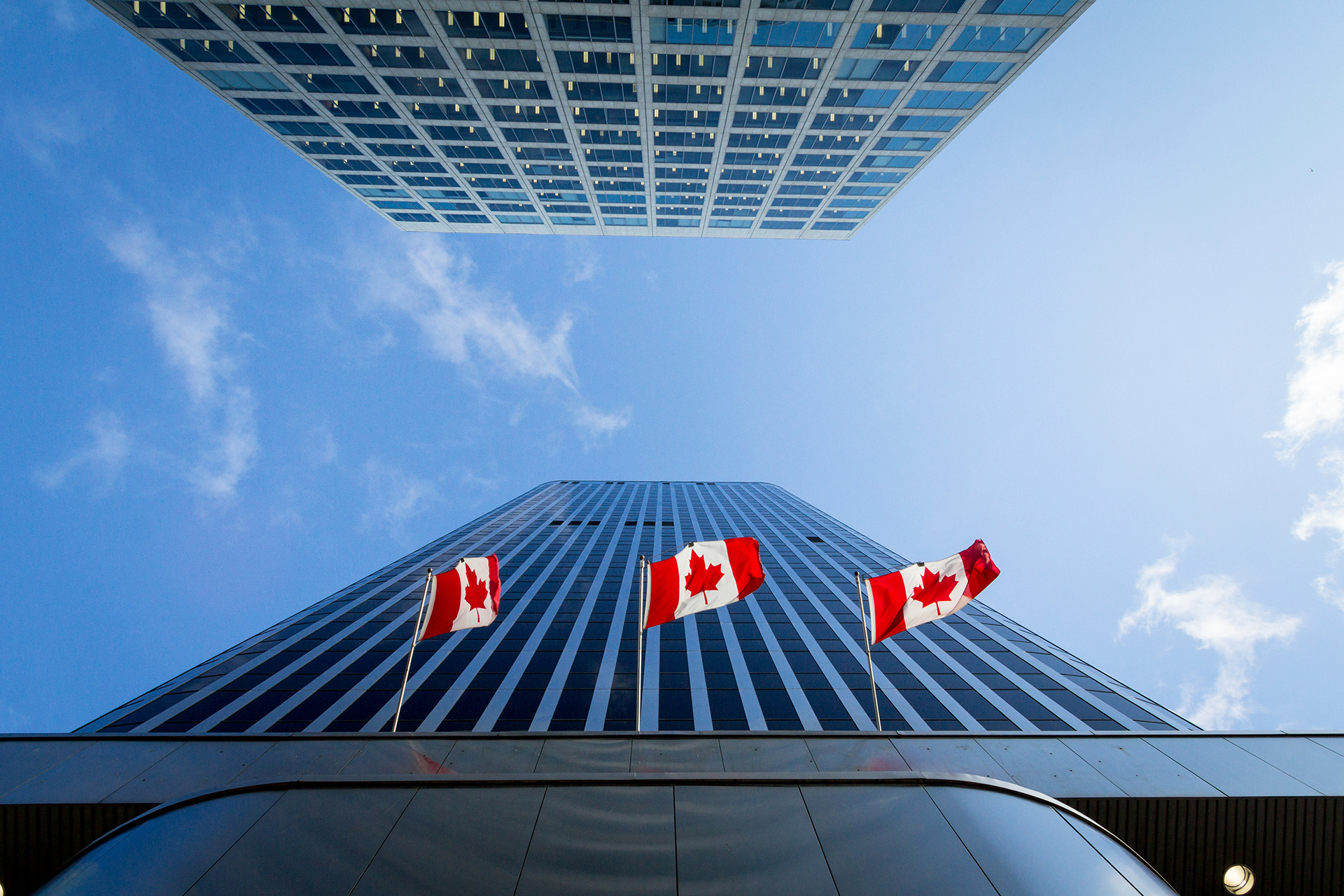 Three Canadian flags in front of a business building